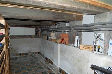 <p>Overzicht van de kelder in de richting van de achtergevel. De gemetselde bak van de oorspronkelijk drijvende kelder is met gemetselde kolommetjes tegen de onderzijde van de balklaag vastgezet. </p>
